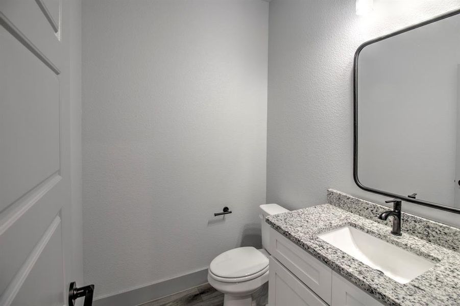 Half bath with vanity, a textured wall, and dark wood-style flooring Half bath with vanity, a textured wall, and dark wood-style flooring