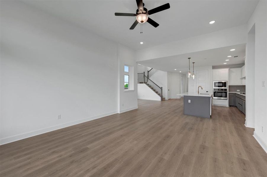 This property features an open-concept living area with light wood-look flooring, a modern ceiling fan, and recessed lighting