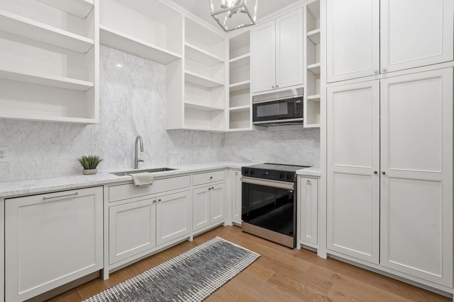 This show-stopping walk-inpantry goes far beyond storage,featuring floor-to-ceiling customshelving, expansive prepcounters, a dedicated sink, plusan electric range and built-inmicrowave—creating a fullyfunctional secondary kitchen.
