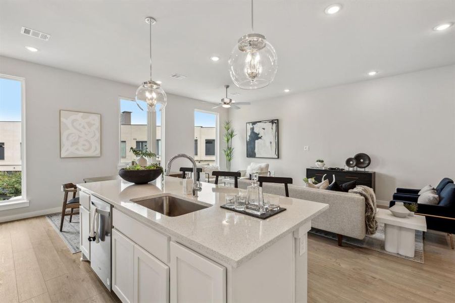 Kitchen with white cabinets, an island with sink, sink, dishwasher, and light hardwood / wood-style flooring