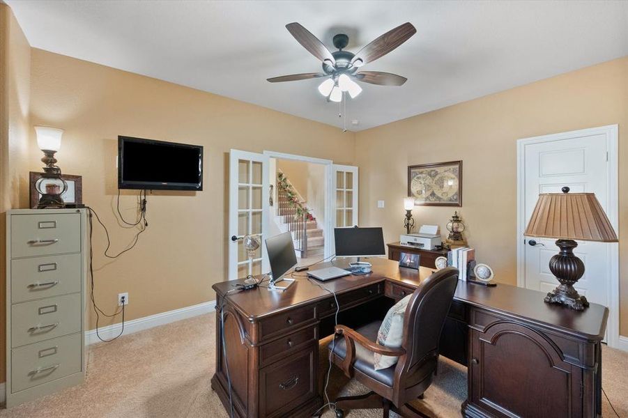 Office space featuring french doors, light colored carpet, and a ceiling fan Office space featuring french doors, light colored carpet, and a ceiling fan