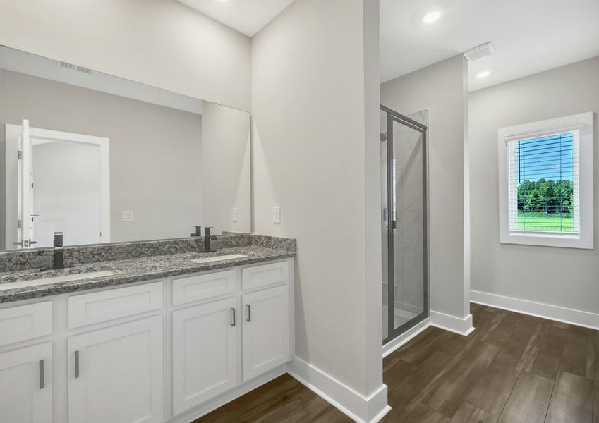 The master bathroom has double sinks and glass-enclosed shower.