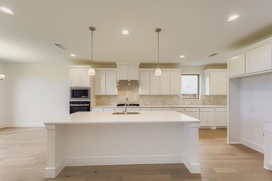 Kitchen featuring hanging light fixtures, white cabinets, recessed lighting, appliances with stainless steel finishes, and backsplash Kitchen featuring hanging light fixtures, white cabinets, recessed lighting, appliances with stainless steel finishes, and backsplash