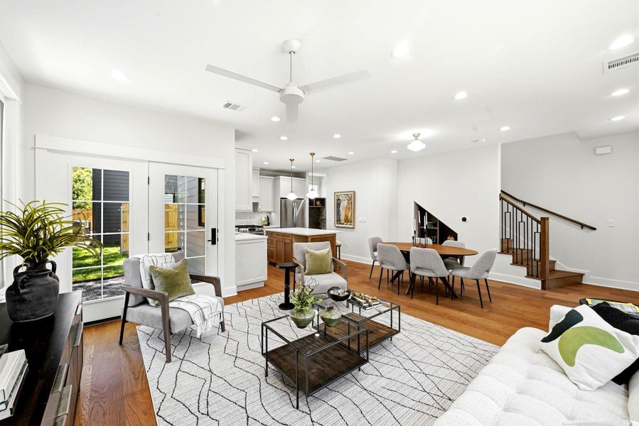 An open concept living area features rich wood flooring, crisp white walls, and bright lighting. An open concept living area features rich wood flooring, crisp white walls, and bright lighting.