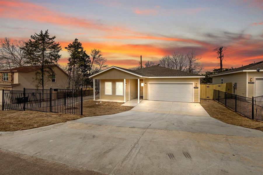 View of front of home with concrete driveway, an attached garage, a gate, fence, and board and batten siding