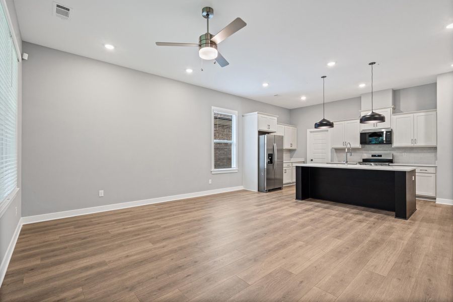 Open-concept living space featuring wood-finish flooring, recessed lighting, and a modern ceiling fan Open-concept living space featuring wood-finish flooring, recessed lighting, and a modern ceiling fan