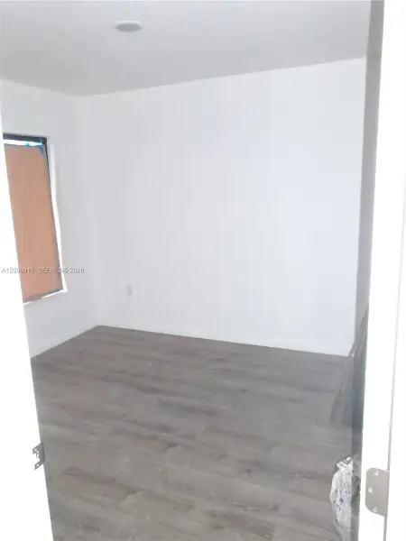 Room interior featuring wood-finish flooring, white walls, and a recessed ceiling light
