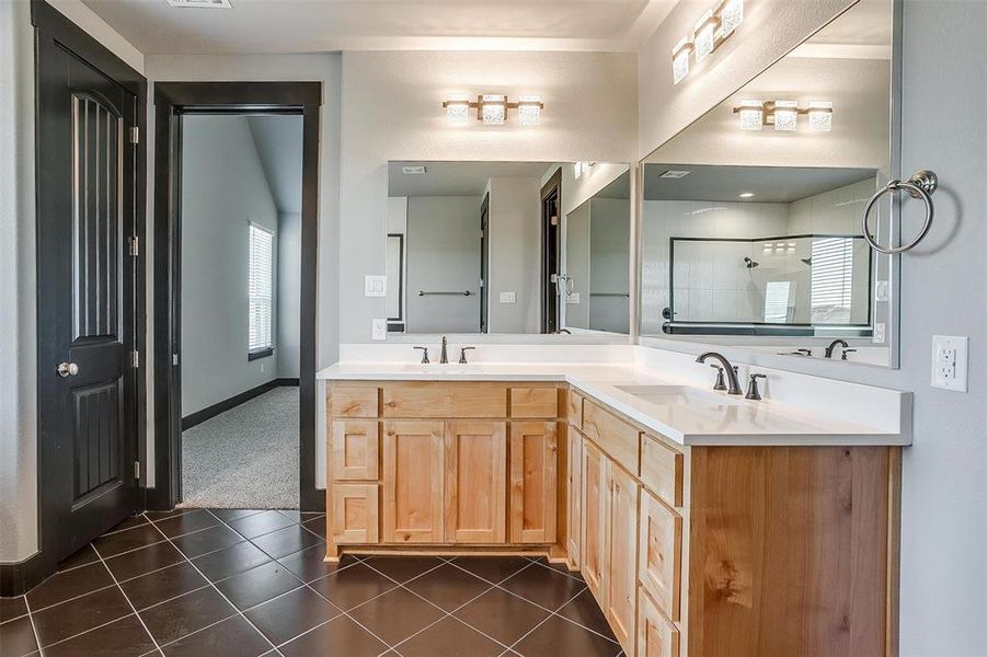 Bathroom with a tile shower, vanity, and tile patterned floors