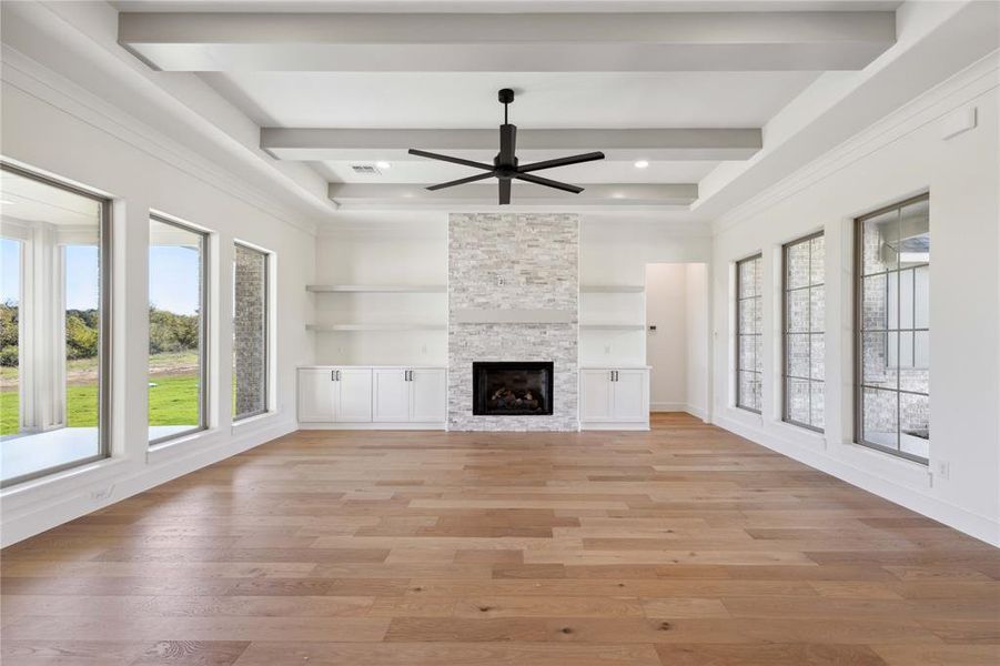 Unfurnished living room featuring a fireplace, light wood-type flooring, ceiling fan, and a healthy amount of sunlight