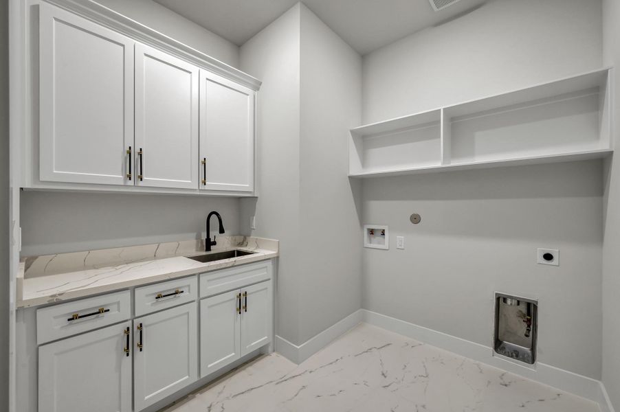 The large utility room with sink, ample counter space, and built-in cabinets for storage. The large utility room with sink, ample counter space, and built-in cabinets for storage.