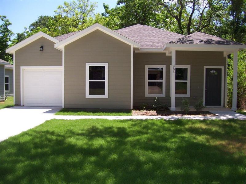 Ranch-style house with a shingled roof, a front lawn, driveway, and a garage