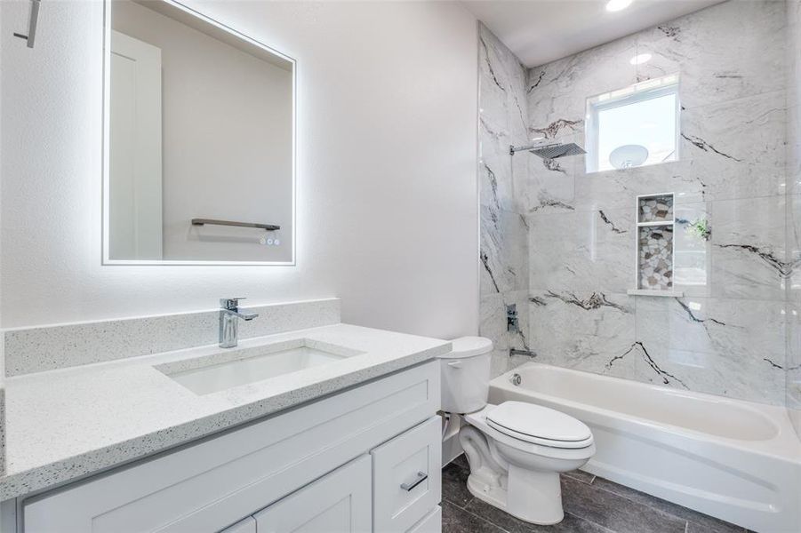 Full bathroom featuring tiled shower / bath combo, vanity, and toilet