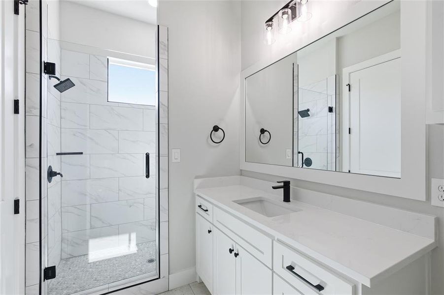 White vanity with a single basin sink, matte black faucet, and white countertop