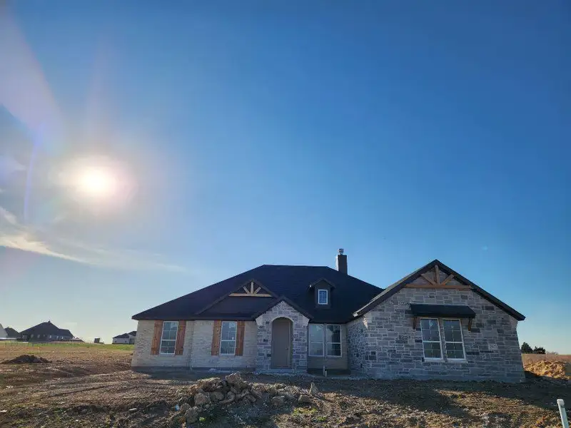 View of front of home featuring a chimney and stone siding