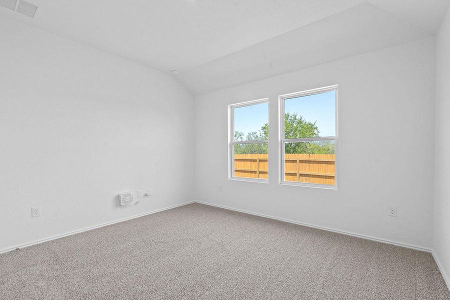 Carpeted empty room with lofted ceiling and baseboards Carpeted empty room with lofted ceiling and baseboards