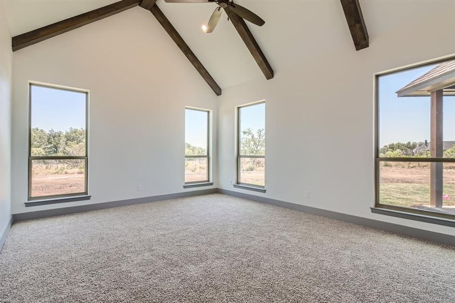 Spare room with carpet floors, beam ceiling, ceiling fan, and high vaulted ceiling