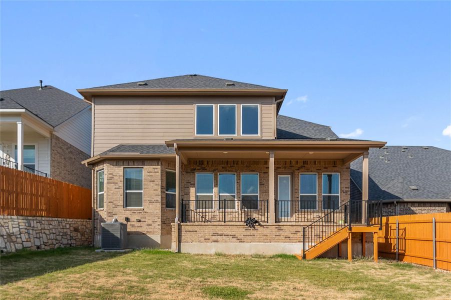 Brick and siding compose this multi-level home's back facade, complete with a covered porch.