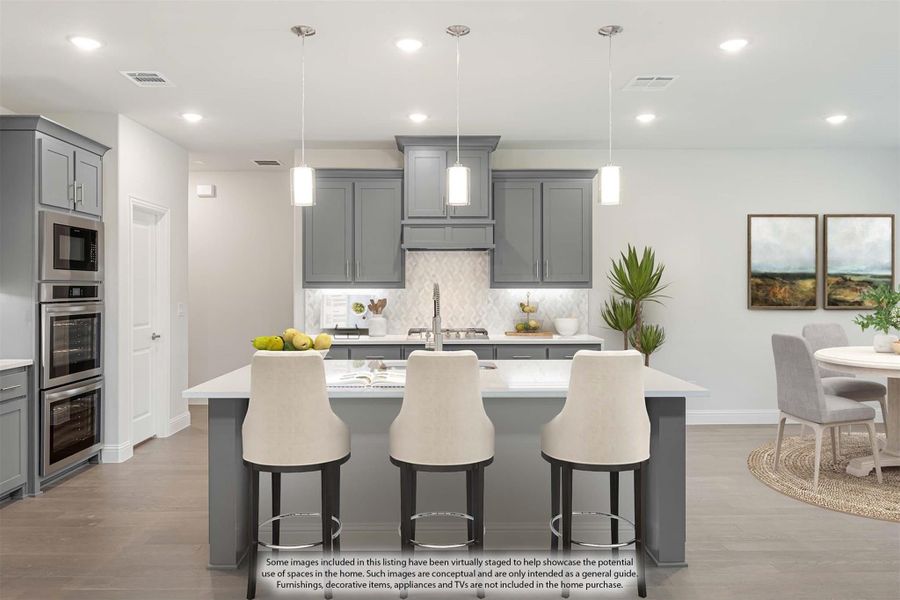 Kitchen with gray cabinets, large island with three bar stools, pendant lights, and stainless steel appliances Kitchen with gray cabinets, large island with three bar stools, pendant lights, and stainless steel appliances