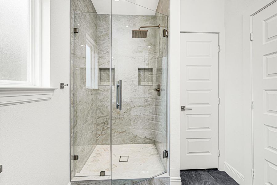 This photo showcases a modern bathroom featuring a sleek glass-enclosed shower with stylish marble tiling and a rainfall showerhead. The space is bright and inviting, enhanced by a nearby window and contemporary finishes. This photo showcases a modern bathroom featuring a sleek glass-enclosed shower with stylish marble tiling and a rainfall showerhead. The space is bright and inviting, enhanced by a nearby window and contemporary finishes.