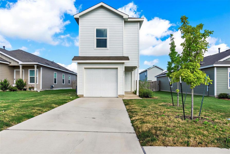 A concrete driveway leads to the attached garage of this two-story home with light siding. A concrete driveway leads to the attached garage of this two-story home with light siding.