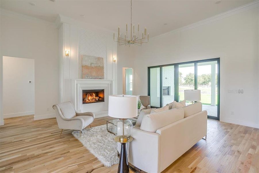 Living room with light hardwood / wood-style floors, ornamental molding, and a towering ceiling