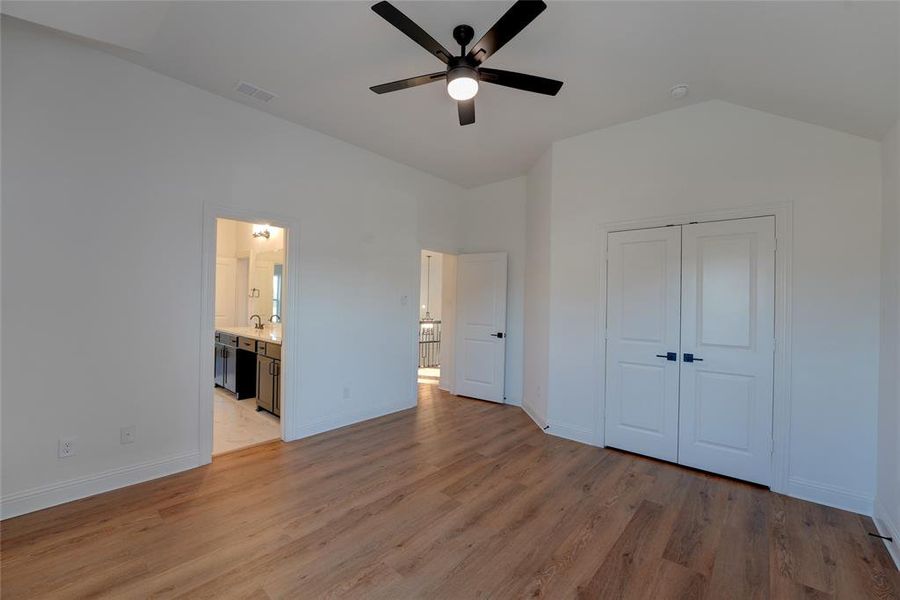 Bedroom with vinyl flooring, baseboards, visible vents, and lofted ceiling