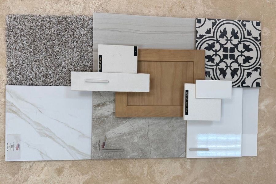 Home design material samples including gray carpet, marble tile, wood cabinet door, and decorative black and white tile laid flat