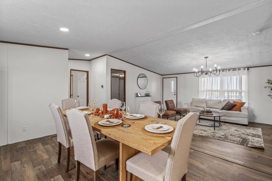 Dining space featuring crown molding, a textured ceiling, dark wood-style floors, and a chandelier