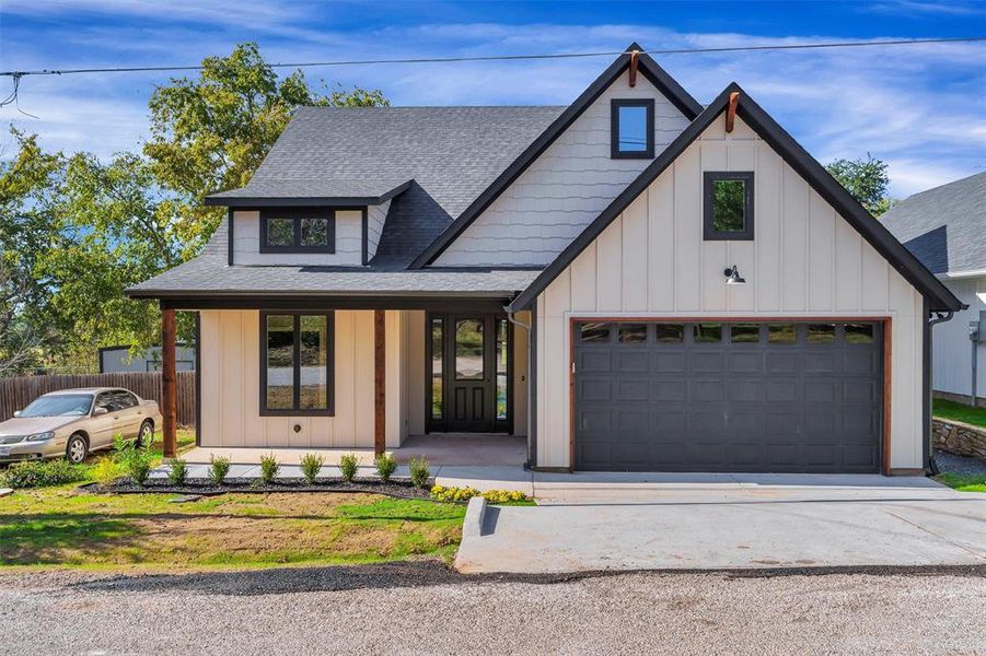 Modern farmhouse style home with roof with shingles, board and batten siding, and covered porch Modern farmhouse style home with roof with shingles, board and batten siding, and covered porch