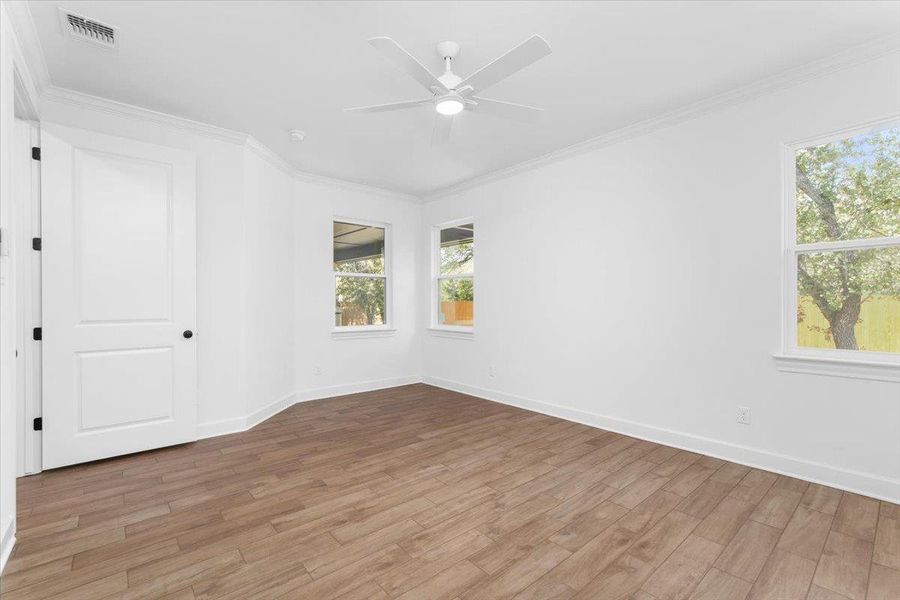 Spare room featuring light wood-style flooring, ornamental molding, a ceiling fan, and baseboards Spare room featuring light wood-style flooring, ornamental molding, a ceiling fan, and baseboards