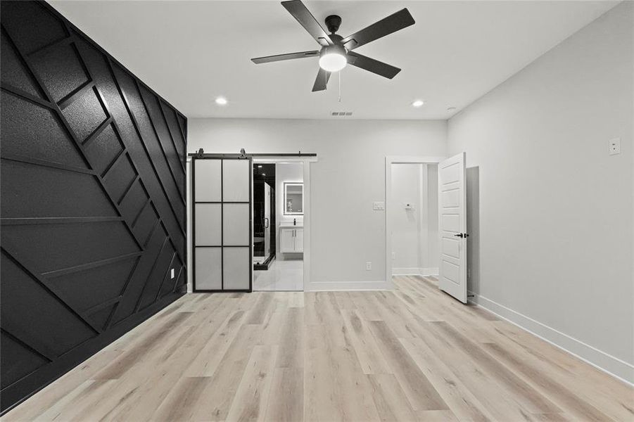 Spare room with a barn door, ceiling fan, and light wood-type flooring