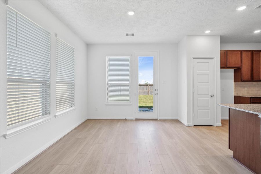 Create lasting memories around the table with family and friends in this inviting dining room! It showcases high ceilings, large windows with privacy blinds, access door to the back patio and yard, vinyl plank flooring, and recessed lighting for a warm and welcoming atmosphere.