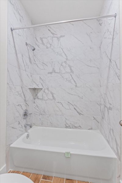 Indulge in a calming soak within this bath with sleek tiled walls.