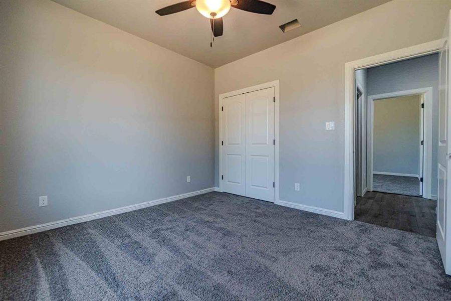 Unfurnished bedroom with dark colored carpet and ceiling fan Unfurnished bedroom with dark colored carpet and ceiling fan