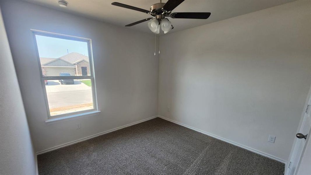 Carpeted room featuring a single window, a ceiling fan with light fixture, and neutral wall paint Carpeted room featuring a single window, a ceiling fan with light fixture, and neutral wall paint