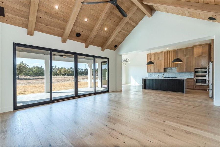 The beautiful Alder wood beams and tongue-and-groove ceiling are complemented by an 88" black three-blade ceiling fan, adding a modern touch, and seamlessly open into the gourmet kitchen.