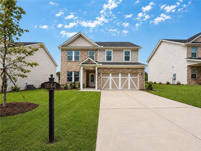 Front exterior of a new home in Berkeley Mill, Cumming, GA, highlighting curb appeal (Image 1). Front exterior of a new home in Berkeley Mill, Cumming, GA, highlighting curb appeal (Image 1).