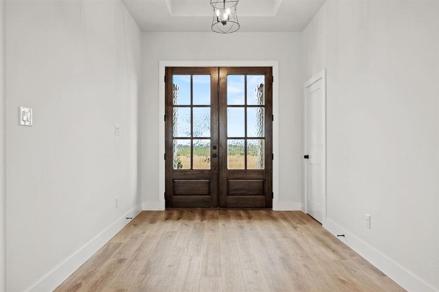 Doorway to outside featuring light wood-style floors, baseboards, and french doors