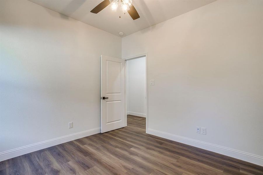 Unfurnished room with dark wood-style flooring and a ceiling fan