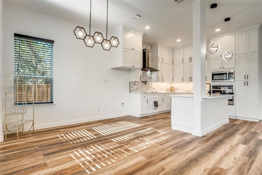 Kitchen with white cabinetry, backsplash, decorative light fixtures, and recessed lighting