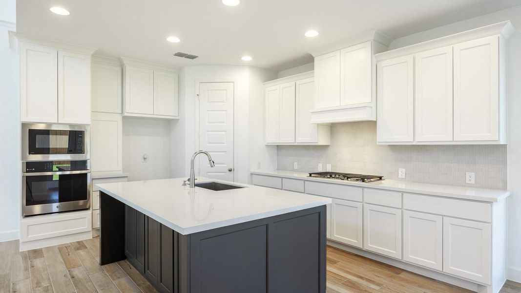 Kitchen featuring white cabinetry, appliances with stainless steel finishes, light stone counters, recessed lighting, and light wood-style floors Kitchen featuring white cabinetry, appliances with stainless steel finishes, light stone counters, recessed lighting, and light wood-style floors