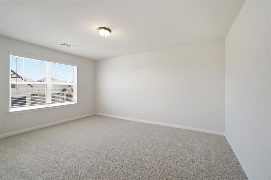 Neutral toned room featuring plush carpet flooring and a large window with white blinds