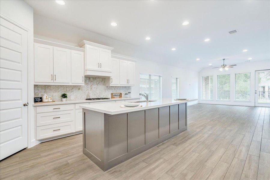 The property features an open-concept kitchen and living area with recessed lighting and light wood-look flooring
