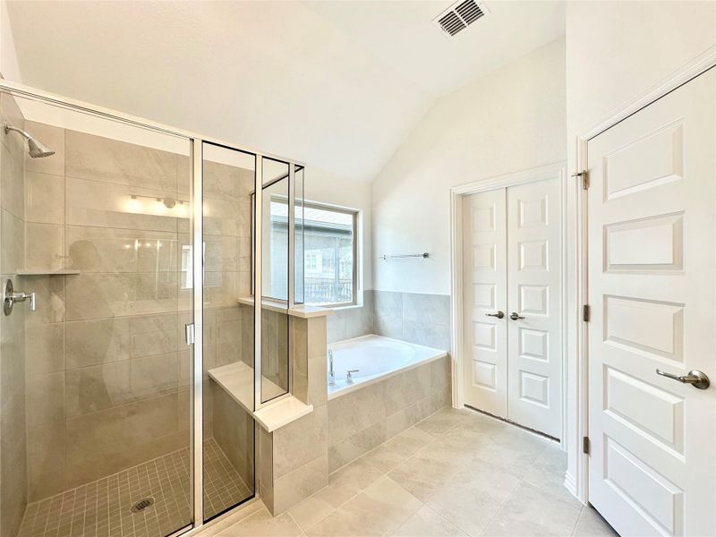 Full bath featuring a stall shower, a bath, lofted ceiling, and tile patterned flooring Full bath featuring a stall shower, a bath, lofted ceiling, and tile patterned flooring