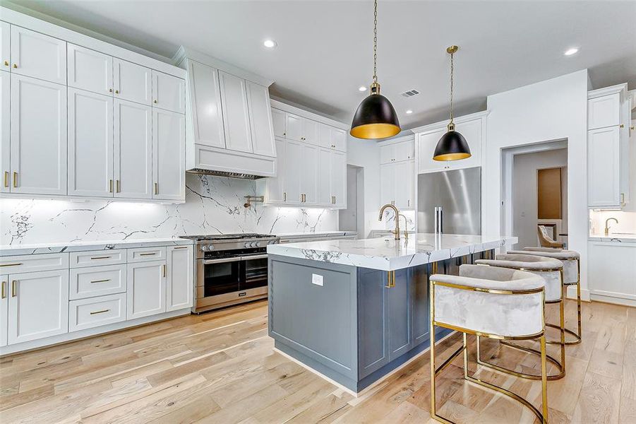 This modern kitchen features sleek white custom cabinetry, a spacious Calacatta Vega quartz island, and Miele stainless steel appliances. Accented by elegant pendant lighting and hardwood floors, it offers a stylish and functional space for cooking and entertaining.