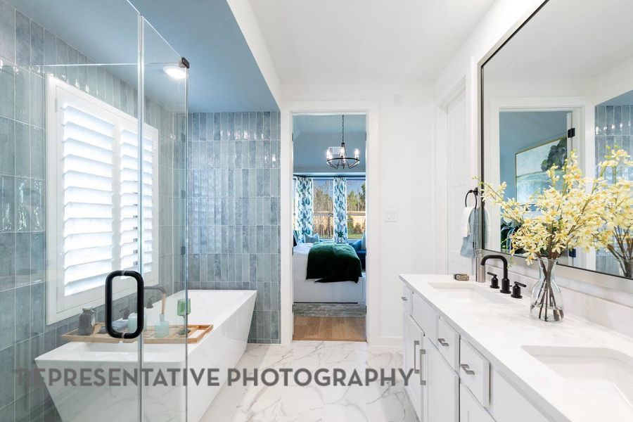 Ensuite bathroom with marble finish floors, a freestanding tub, double vanity, a chandelier, and tile walls Ensuite bathroom with marble finish floors, a freestanding tub, double vanity, a chandelier, and tile walls