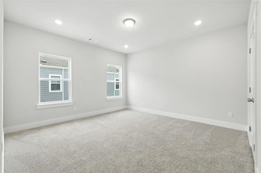 Empty room with light carpet and recessed lighting