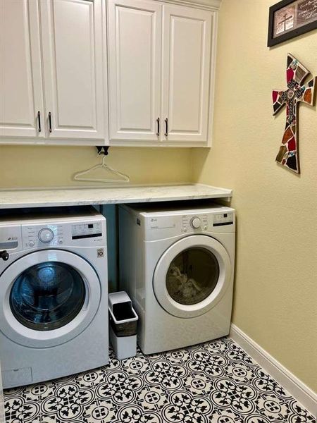 Washroom with cabinets, light tile patterned flooring, and washer and dryer