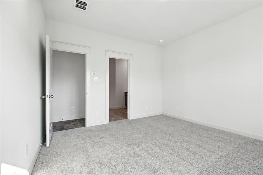 Unfurnished bedroom with light colored carpet and baseboards Unfurnished bedroom with light colored carpet and baseboards