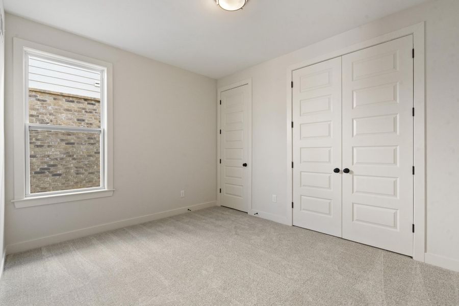 Neutral tone wall paint, light gray carpet, white trim, five-panel doors with black hardware, and a single window Neutral tone wall paint, light gray carpet, white trim, five-panel doors with black hardware, and a single window